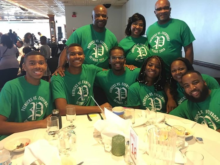 Family gathered around a table in green reunion shirts